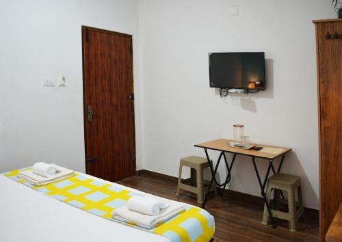 a room with a bed and a table with a tv at EDEN Paradisee in Ooty
