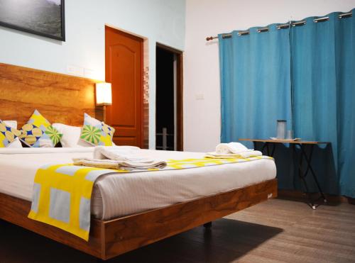 a bedroom with a large bed with blue curtains at EDEN Paradisee in Ooty