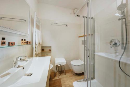 La salle de bains blanche est pourvue d'un lavabo et d'une douche. dans l'établissement Hotel Panda Cortina- ricarica auto elettriche, à Cortina dʼAmpezzo