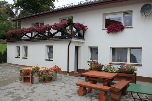 a white house with a picnic table and flowers at Cztery Pory Roku in Jeżów Sudecki