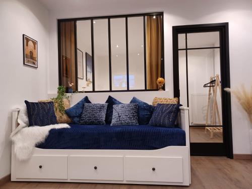 ein weißes Sofa mit blauen Kissen in einem Zimmer in der Unterkunft Le petit Dubaï in Douai