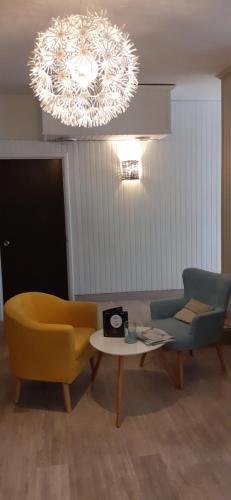 a living room with a chair and a table and a chandelier at Fuzei Hôtel Lorient-Lanester in Lanester