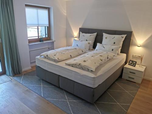 um quarto com uma cama grande com lençóis brancos e almofadas em Ferienwohnung Wiesenblick em Bad Hindelang