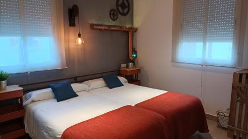 a bedroom with a large white bed with blue pillows at El Duende del Tejar in El Gastor