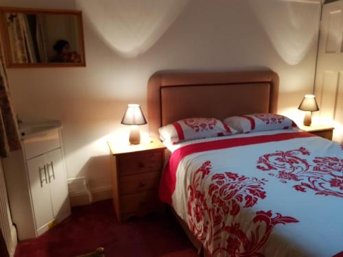 a bedroom with a bed and a nightstand with two lamps at Guest House Ellipse - Finchley in Finchley