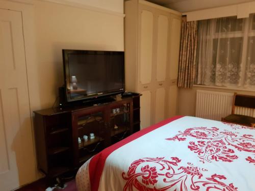 um quarto com uma cama e uma televisão de ecrã plano em Guest House Ellipse - Finchley em Finchley