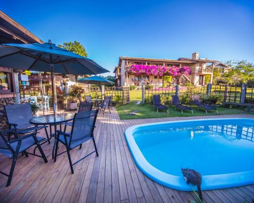 a patio with a table and chairs next to a pool at Pousada Capitão Cook in Praia do Rosa