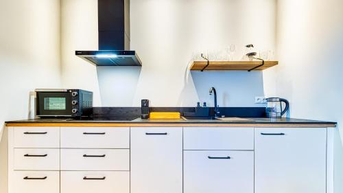 a kitchen with a sink and a microwave at Apartamenty VIP Centrum - Wczasowa 17 by Royal Aparts in Świeradów-Zdrój