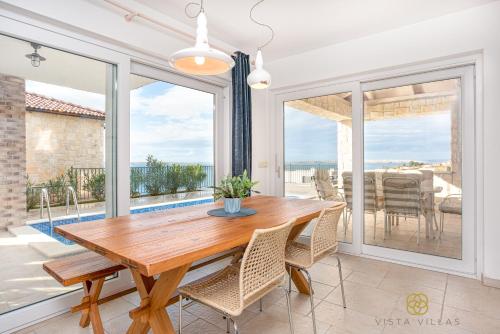 een eetkamer met een houten tafel en een groot raam bij Vista Villas - Lazy Days Apartment Villa N in Ražanac
