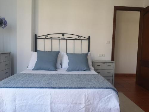 a bedroom with a large bed with blue pillows at Apartamento Bohemia in Villanueva de Arosa