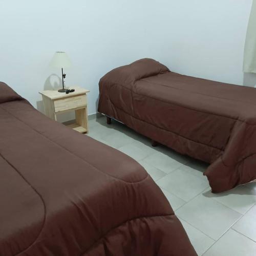 two beds and a table in a room at Cabañas Corazon de Maria in Merlo