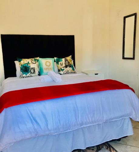 a large bed with a red and blue blanket at CapitalT Luxury Guest House in Germiston
