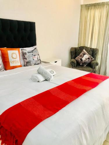 a bedroom with a red and white bed and a chair at CapitalT Luxury Guest House in Germiston