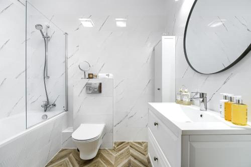 a white bathroom with a toilet and a mirror at EXCLUSIVE Nautica Apartments in Szczecin
