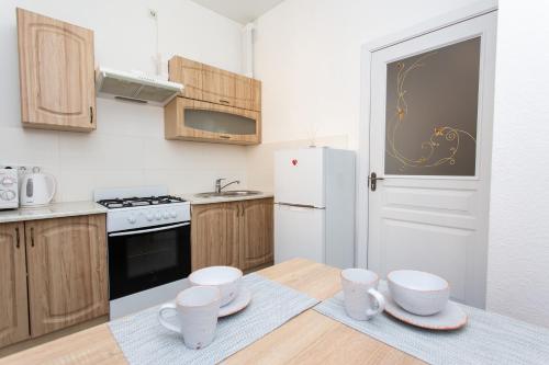 a kitchen with wooden cabinets and a white refrigerator at Центр. Хмельницького 6а. 2 кімнати. in Ternopilʼ