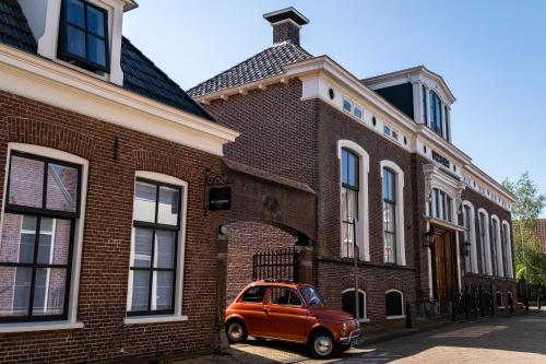 a red car parked in front of a brick building at Het Weeshuis in Bolsward