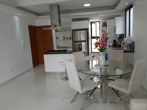 a kitchen with a glass table and white chairs at AMG Suites Apartment in Santo Domingo