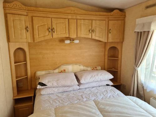 a bedroom with a bed with wooden cabinets at 6 Berth Central heated on The Chase (Balmoral) in Ingoldmells