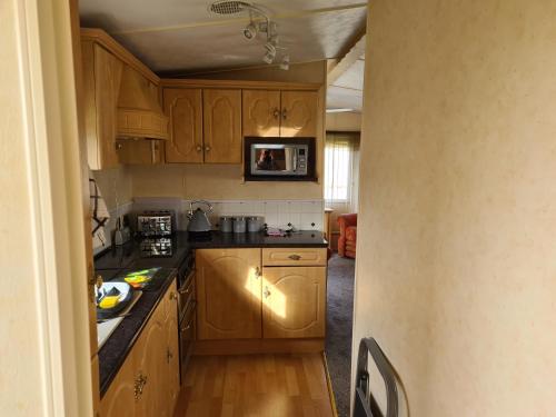 a small kitchen with wooden cabinets and a microwave at 6 Berth Central heated on The Chase (Balmoral) in Ingoldmells