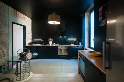 een keuken met blauwe kasten en een tafel. bij Villa Courreau - Maison de maitre in Vendays-Montalivet