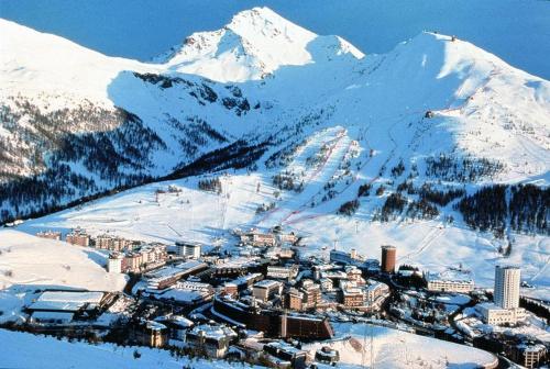 a city in the snow with a snow covered mountain at Villaggio Olimpico in Sestriere