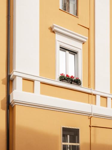 a yellow building with a window with red flowers on it at Maison boutique Matteotti in Matera