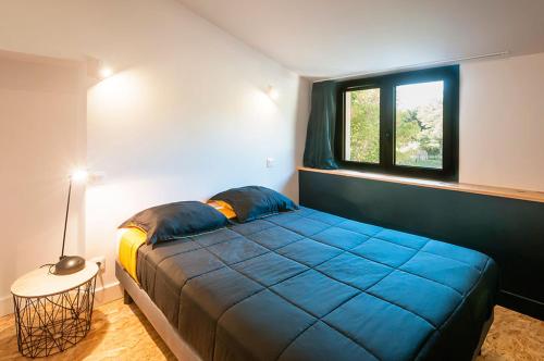 een slaapkamer met een blauw bed en een raam bij Villa Courreau - Maison de maitre in Vendays-Montalivet