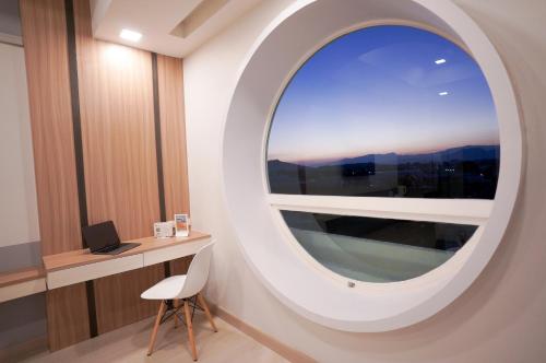a round mirror in a room with a desk and a window at The Space Hotel Chiang Rai in Chiang Rai