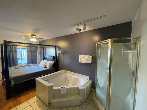 een badkamer met een bad en een bed bij Best Budget Inn in Bastrop
