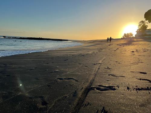 two people walking on the beach at sunset at Apartamento Tropical Playa Coronado in Playa Coronado