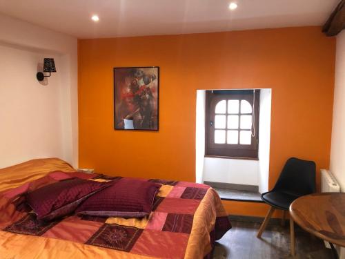 a bedroom with orange walls and a bed and a window at En toute simplicité in Bielle