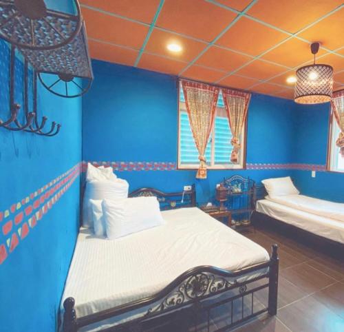 a bedroom with two beds in a blue room at 熊居民宿Lala Mountain Bear Farm in Hualing