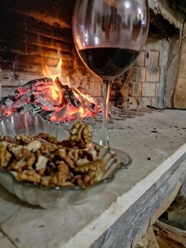 a glass of wine and a plate of food next to a fire at Къща За Гости Уют Guest House Cozy in Starosel