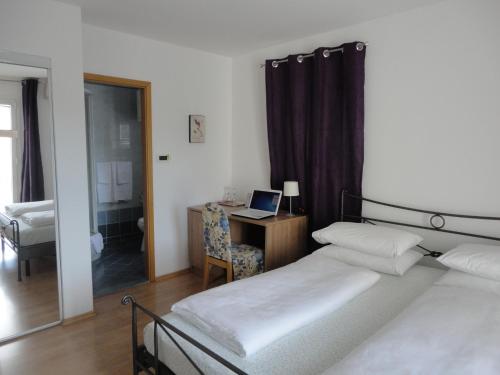 a bedroom with a bed and a desk with a laptop at Pink Inn in Podstrana