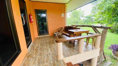 a porch with a wooden bench and a table at Moon River Resort Phimai in Phimai