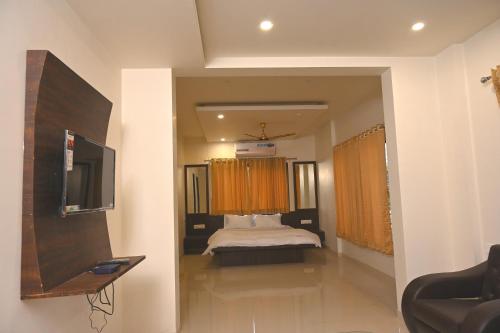a bedroom with a bed and a tv in a room at Majestic Hotel in Nashik
