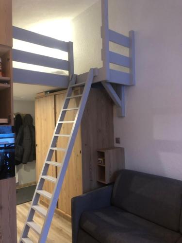 a loft bed in a room with a couch at La chaumière des neiges in Châtel