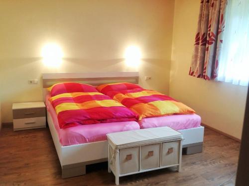 um quarto com uma cama com cobertores coloridos em s'Hoamatl em Neukirchen am Grossvenediger