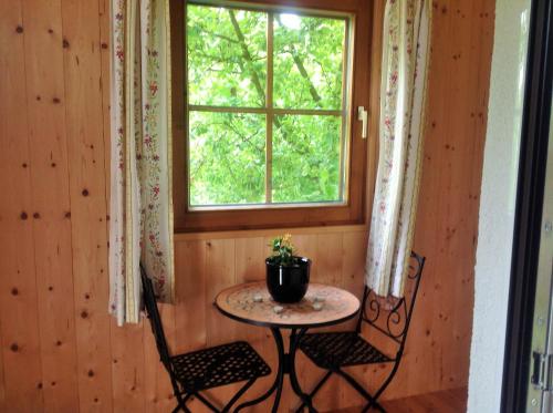 einen Tisch und zwei Stühle in einem Zimmer mit Fenster in der Unterkunft s'Hoamatl in Neukirchen am Großvenediger