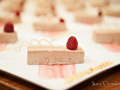 a piece of cake on a plate with a raspberry on top at The Senator Hotel & Conference Center Timmins in Timmins