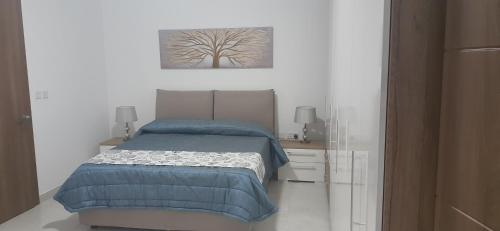 a bedroom with a bed and a tree painting on the wall at Sayonara in Marsaxlokk
