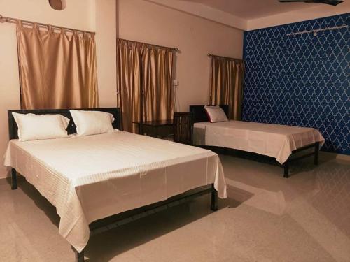 um quarto com 2 camas e uma parede azul em Nilachal Homes em Guwahati