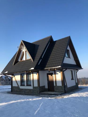 a house with a black roof in the snow at Domek Góralski Kąty na Wierchu in Szaflary