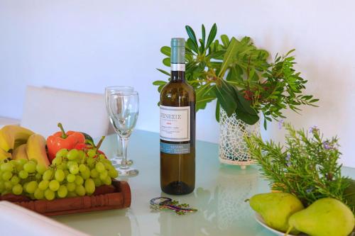 a bottle of wine sitting on a table with fruit at Vista Mare Isavros in Arvanitakaíïka