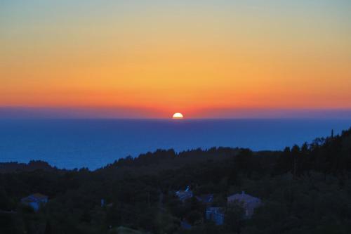 a sunset over the ocean with the sun in the sky at Vista Mare Isavros in Arvanitakaíïka
