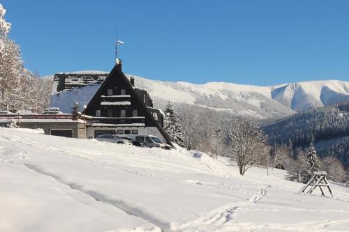 a ski lodge in the snow with mountains in the background at Pension Krakonoš in Špindlerův Mlýn