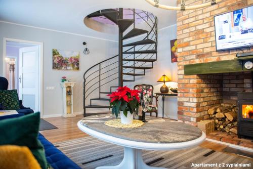 a living room with a spiral staircase and a table with red flowers at Hubertówka in Somonino