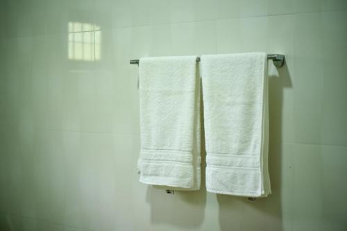 two white towels hanging on a towel rack in a bathroom at Tamarind Tamarind Resort, Tourist Board Approved in Habarana