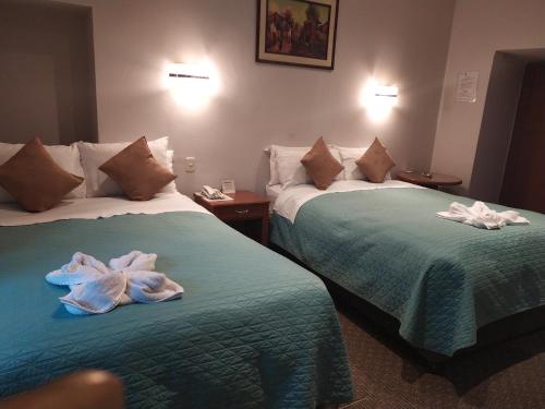 Dos camas en una habitación de hotel con toallas. en HOTEL AMTALLPA San Blas Inn, en Cusco