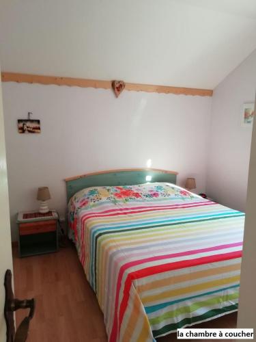 - une chambre avec un lit et une couverture rayée colorée dans l'établissement Le Chalet Bel Air, à Oderen